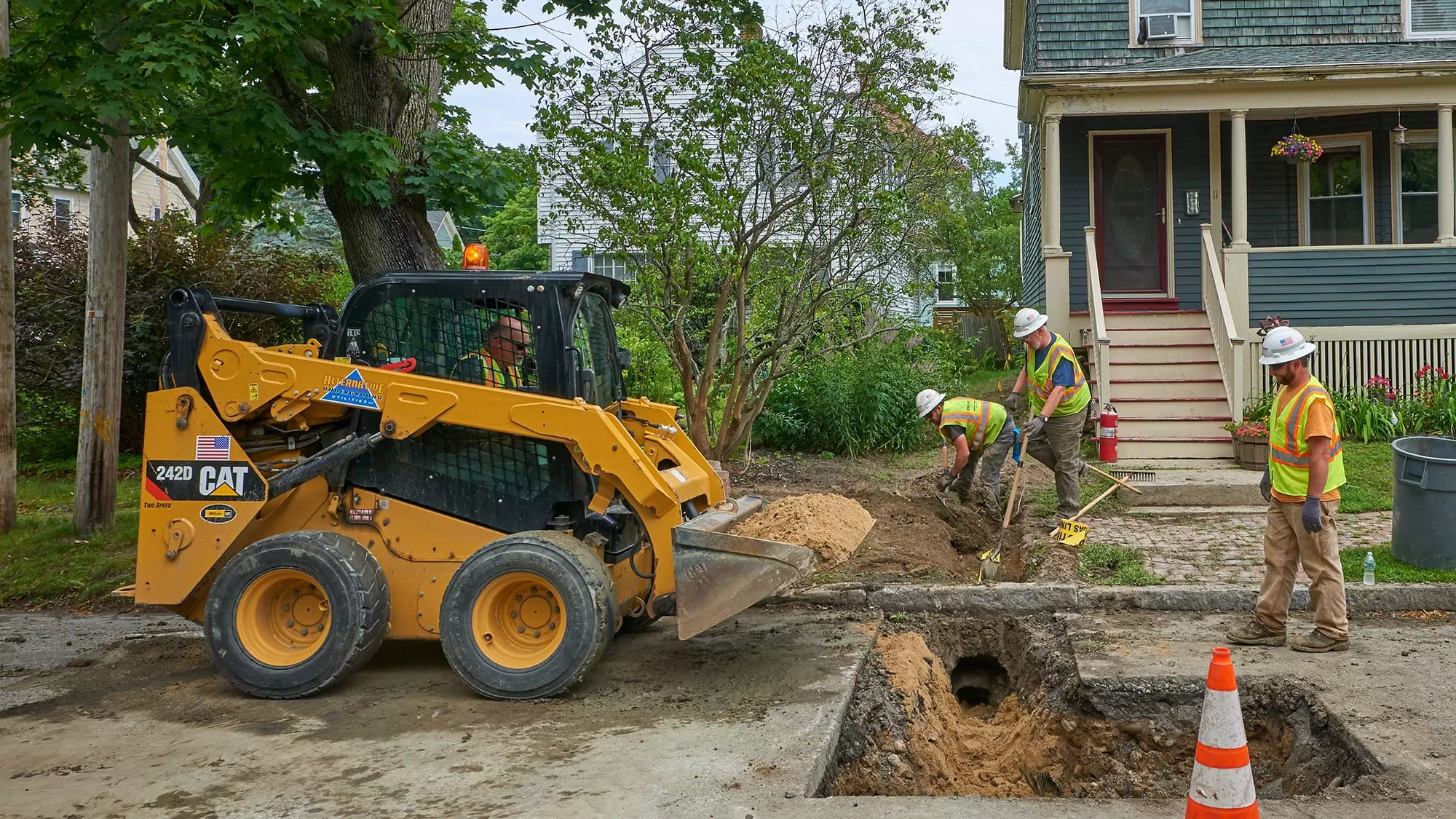Skid Steer digging out a pipe in the front of a house