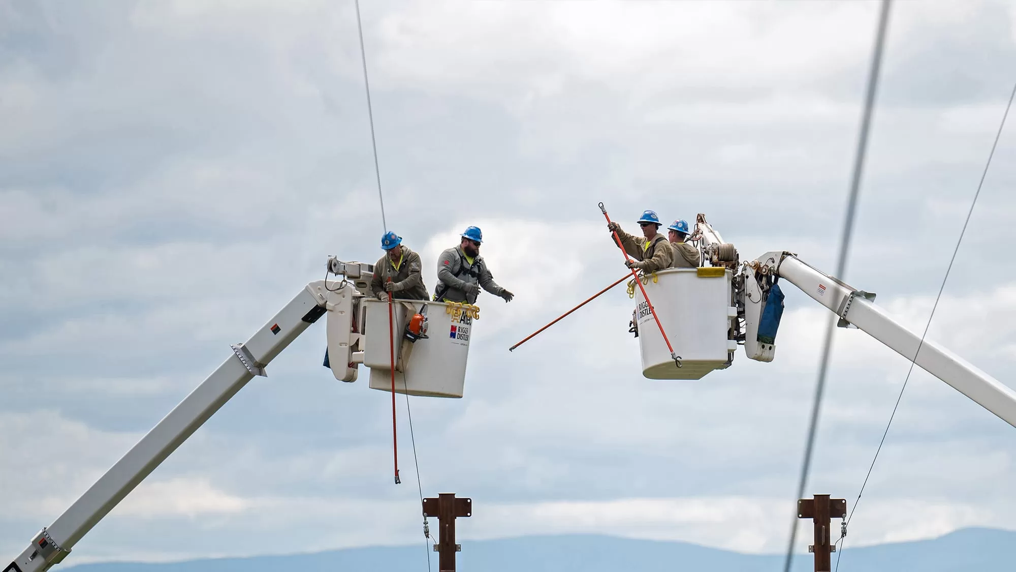 workers in cranes fixing power lines