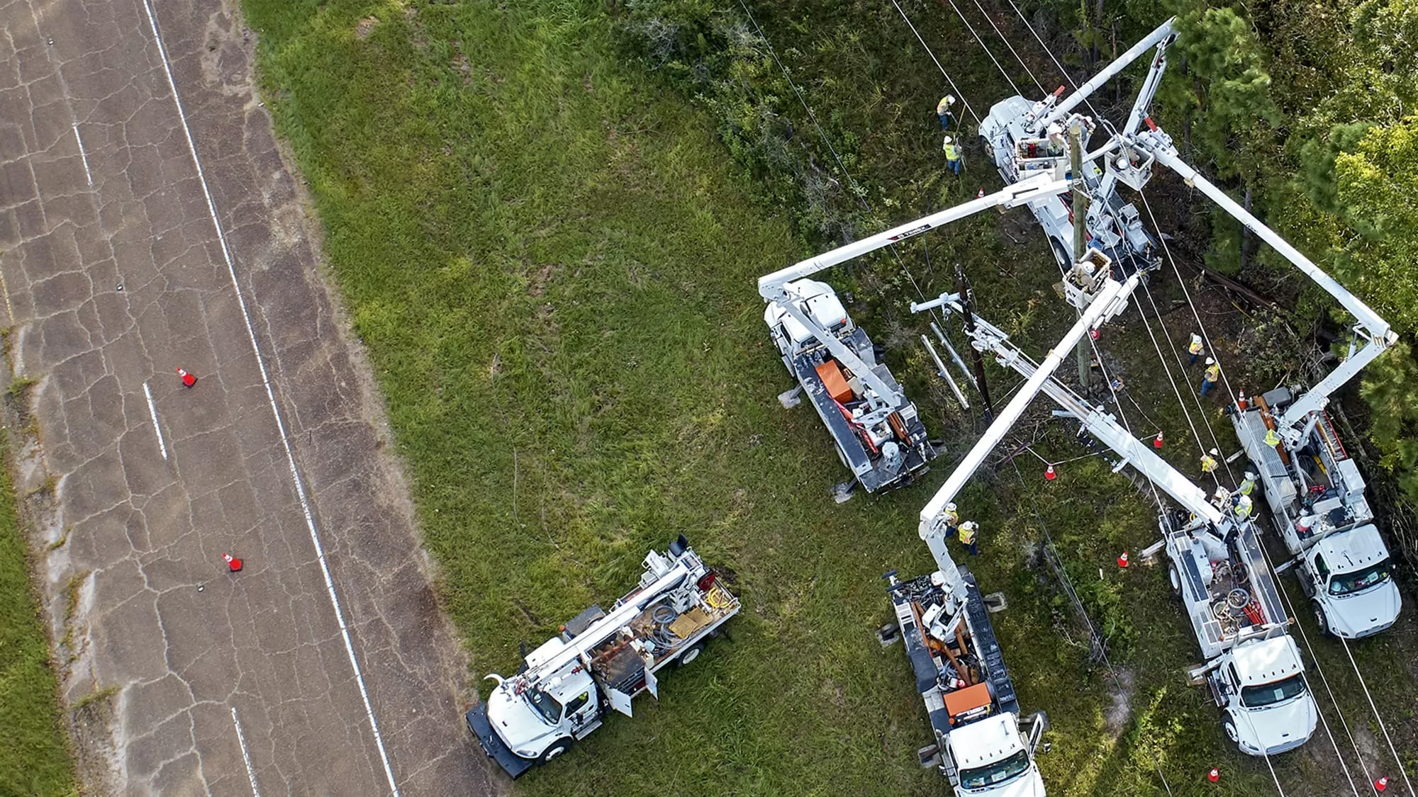 Overview of workers in cranes fixing electric poles and wires