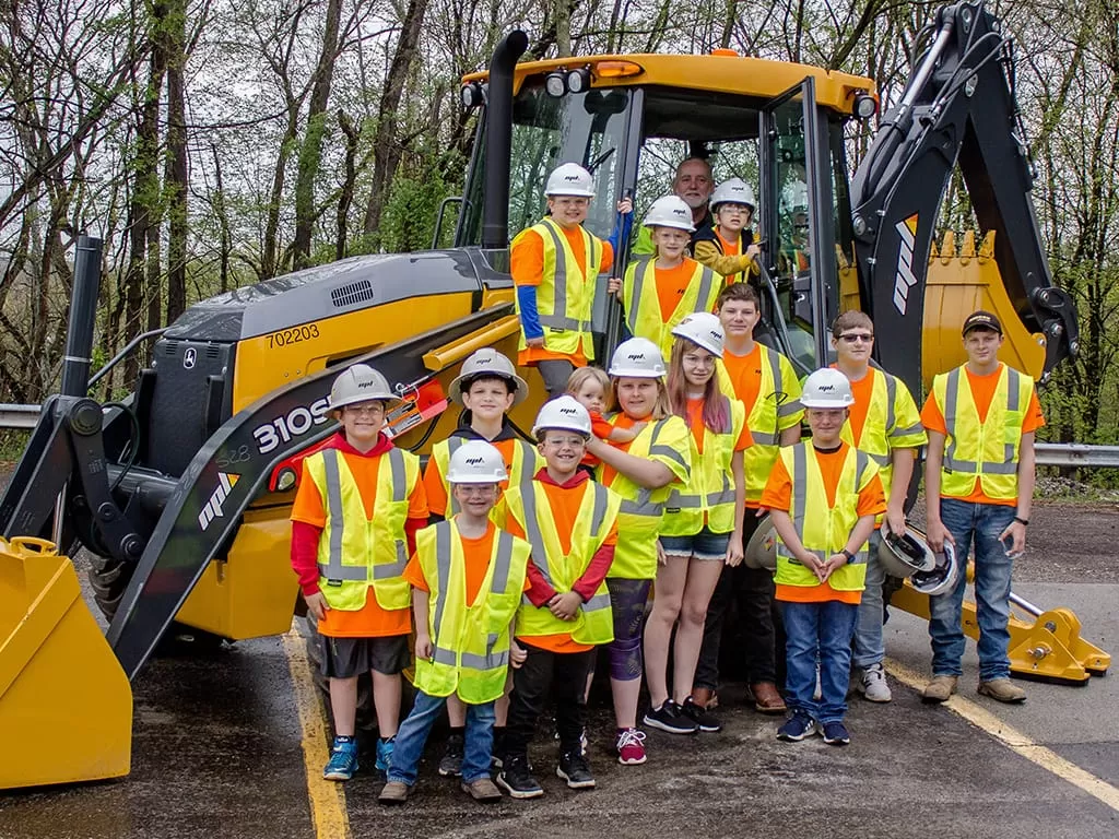 Bring Your Child To Work Day- 14 kids posing in front of tractor wearing PPE
