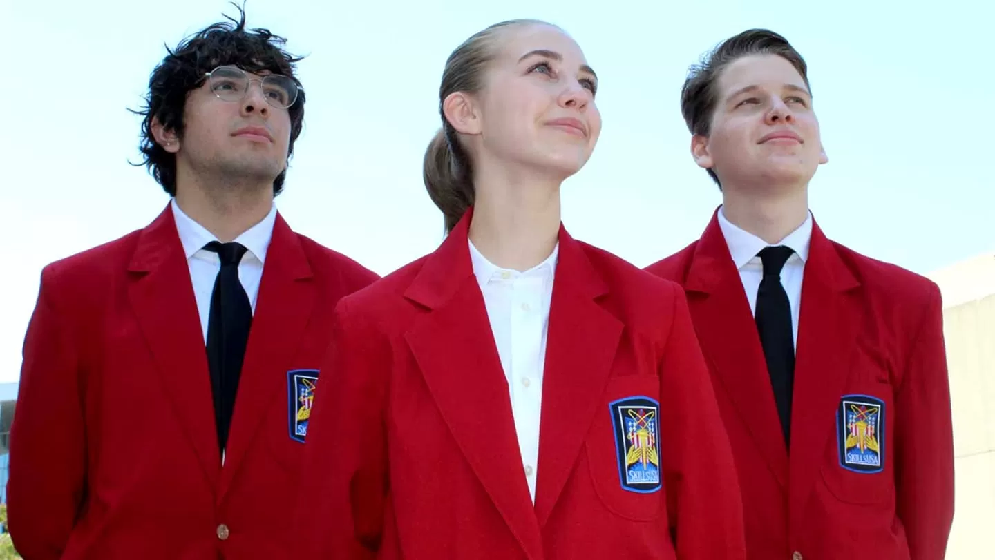 3 teens wearing red blazers looking up at the sky
