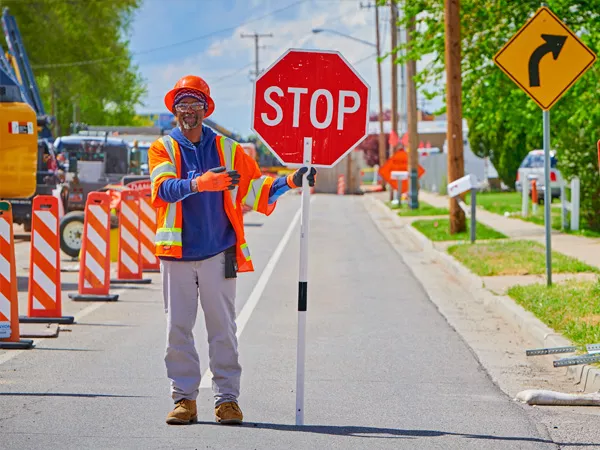 worker holding a stop sign to stop traffic around the construction site
